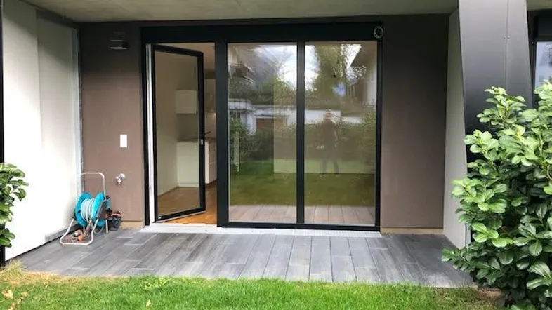 Terrasse mit Zugang zum Garten und großen Glasschiebetüren, die in den Wohnbereich führen.