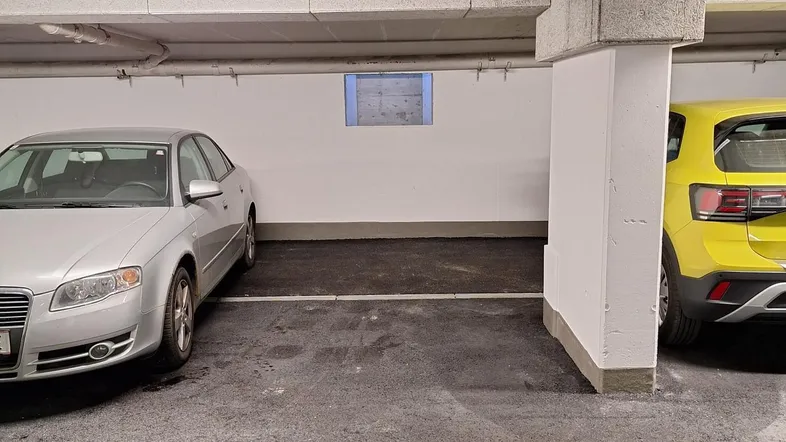 Helle Tiefgarage mit mehreren Stellplätzen und moderner Beleuchtung an der Decke.