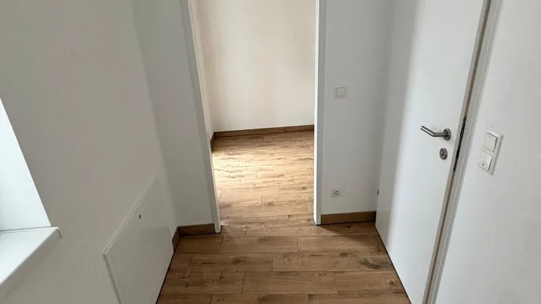 Heller Flur mit modernem Holzboden, der zu weiteren Räumen der Wohnung führt.