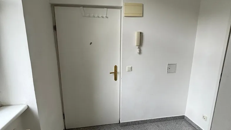 Heller Eingangsbereich mit Fliesenboden, Fenster und Gegensprechanlage, in gutem Zustand.