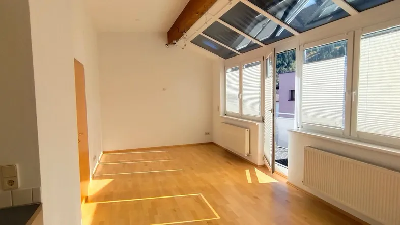 Lichtdurchfluteter Wohnraum mit Holzfußboden, großen Fenstern und Dachfenstern.