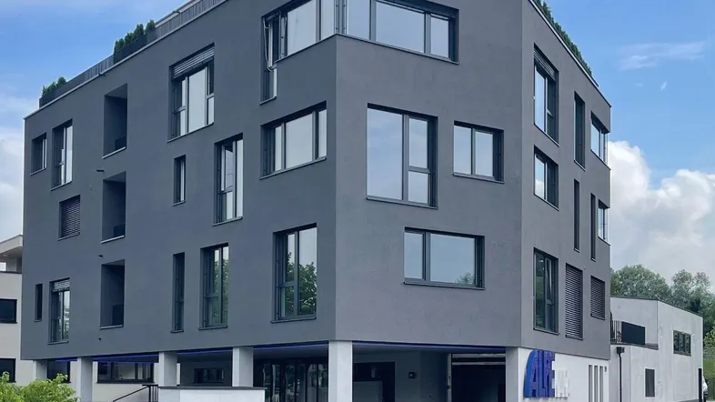 Modernes Bürogebäude mit dunkler Fassade und großen Fenstern, umgeben von einer Baustelle.