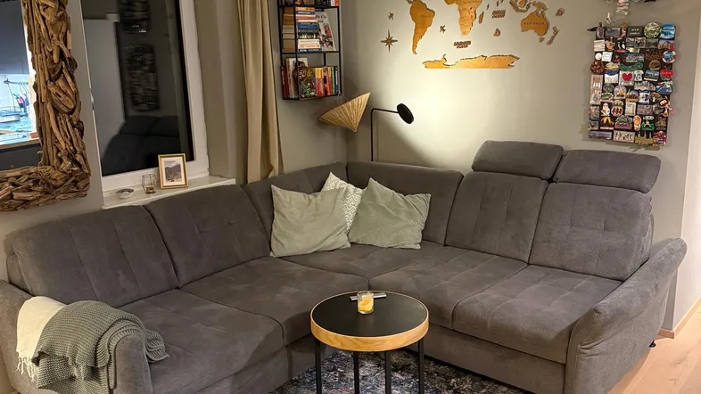 Gemütliches Wohnzimmer mit großem Ecksofa, Holzboden und dekorativer Weltkarte an der Wand.
