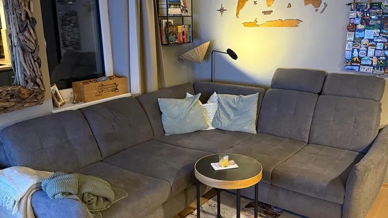 Gemütliches Wohnzimmer mit großem Ecksofa, Holzboden und dekorativer Weltkarte an der Wand.