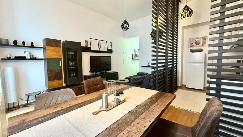 Geräumiger Wohn- und Essbereich mit Holztisch, bequemen Stühlen und moderner Einrichtung.