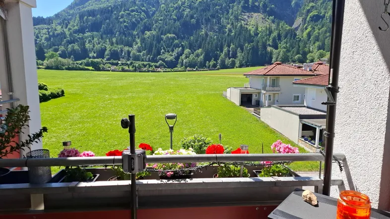 Geräumiger Balkon mit atemberaubendem Blick auf die umliegenden Berge und grüne Wiesen.