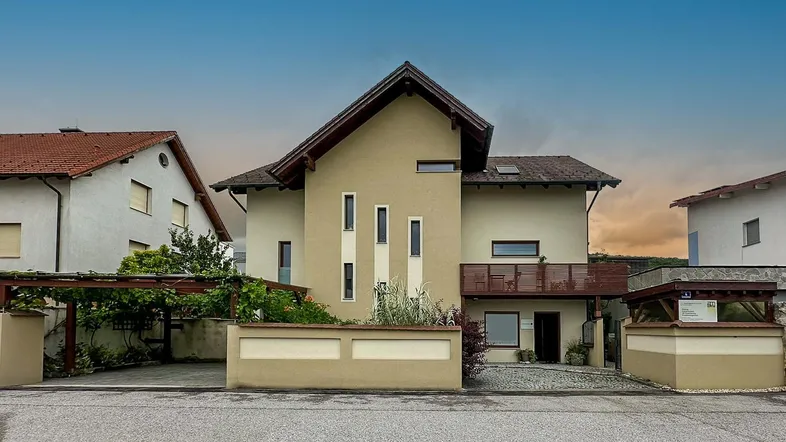 Modernes Einfamilienhaus mit Satteldach und Carport in einer Wohnsiedlung.