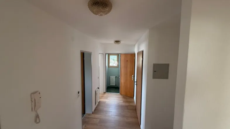 Heller Flur mit Laminatboden und mehreren Türen, der zu weiteren Räumen führt.