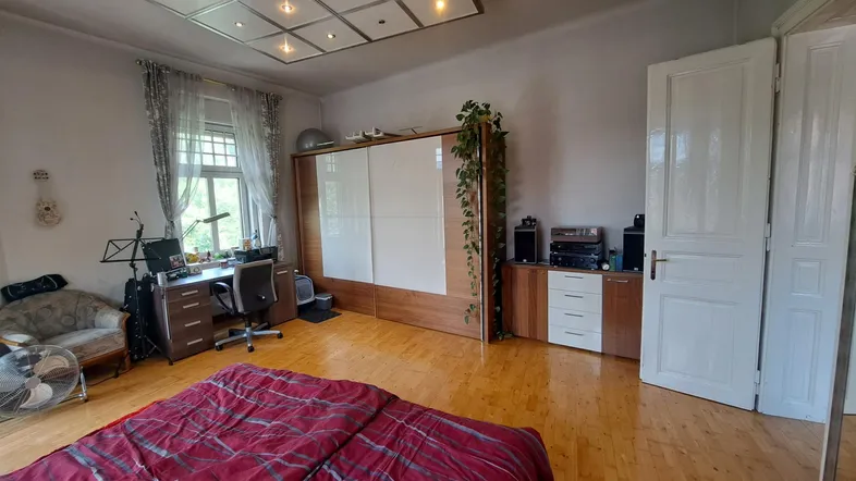 Geräumiges Schlafzimmer mit Holzboden, großem Kleiderschrank und integriertem Arbeitsbereich am Fenster.