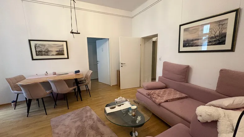 Geräumiger Wohn-Essbereich mit gemütlichem Sofa, Esstisch und hellem Parkettboden.