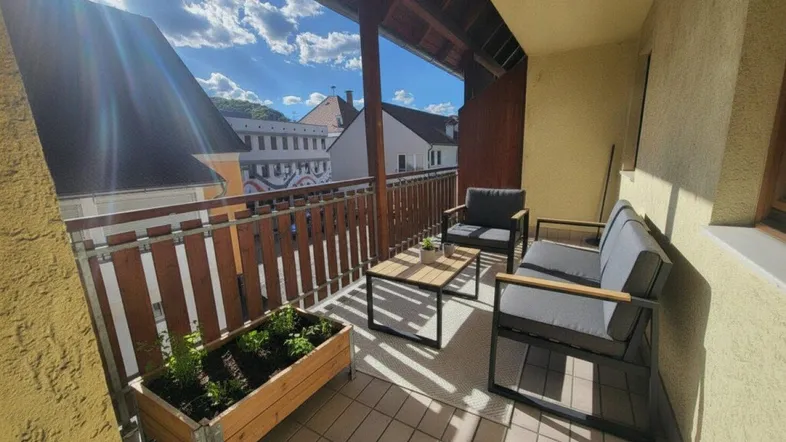 Sonniger Balkon mit bequemen Gartenmöbeln und Blick auf die umliegenden Gebäude.