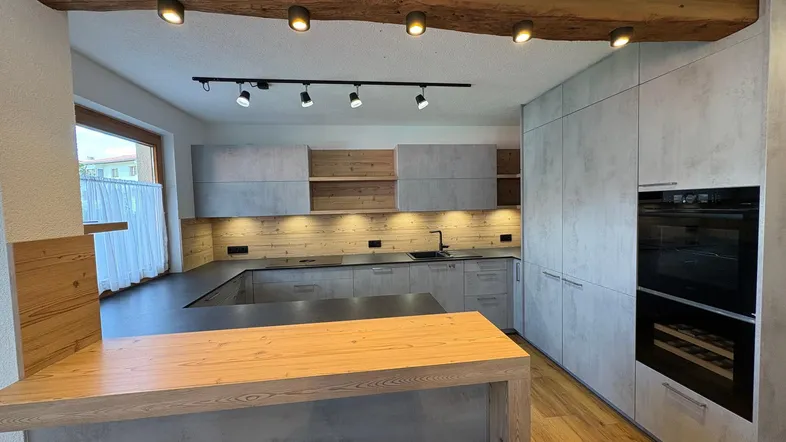 Moderne Küche mit Kücheninsel, integrierten Geräten und Holzbalken an der Decke.