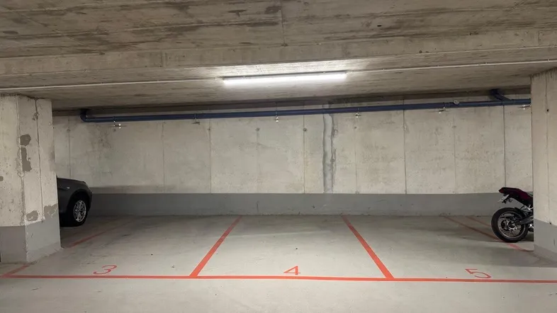 Tiefgarage mit markierten Stellplätzen, Betonwänden und Decke sowie effizienter Beleuchtung.
