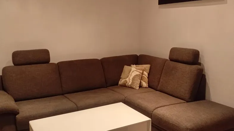 Gemütliches Wohnzimmer mit großem Ecksofa, modernem Couchtisch und einem Wandbild.