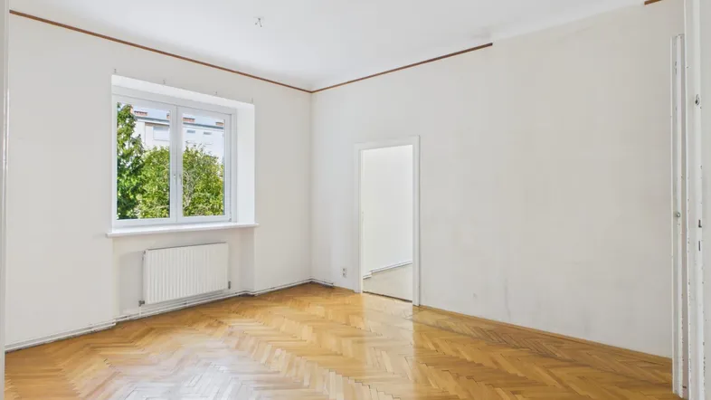 Helles Zimmer mit Fischgrätparkett und Blick ins Grüne, ideal als Wohn- oder Schlafzimmer.