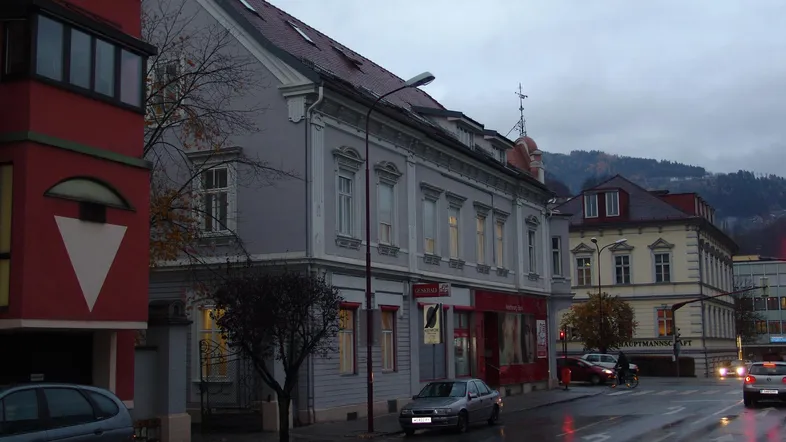 Abendliche Straßenansicht mit historischen und modernen Gebäuden unter bewölktem Himmel in der Stadt.