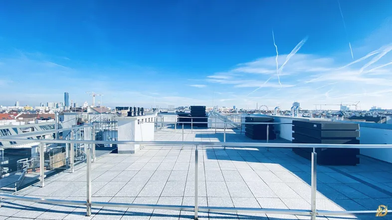 Weitläufige Dachterrasse mit Panoramablick über die Stadt und umliegende Gebäude unter blauem Himmel.