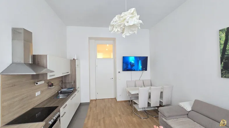 Moderne Wohnküche mit Essbereich und Sofa, ausgestattet mit hellen Möbeln und Holzboden.
