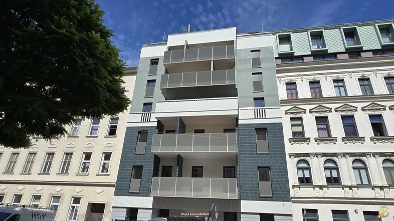 Moderne Fassade eines Mehrfamilienhauses mit Balkonen und großen Fenstern.