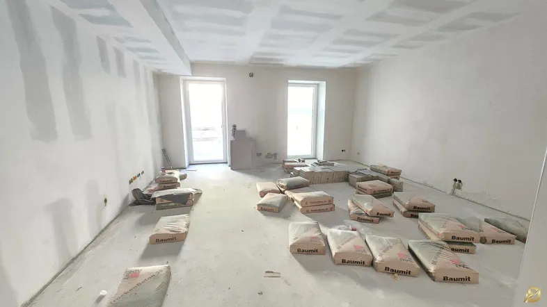 Unfertiger Raum im Rohbau mit Trockenbauwänden und Baumaterialien auf dem Betonboden.