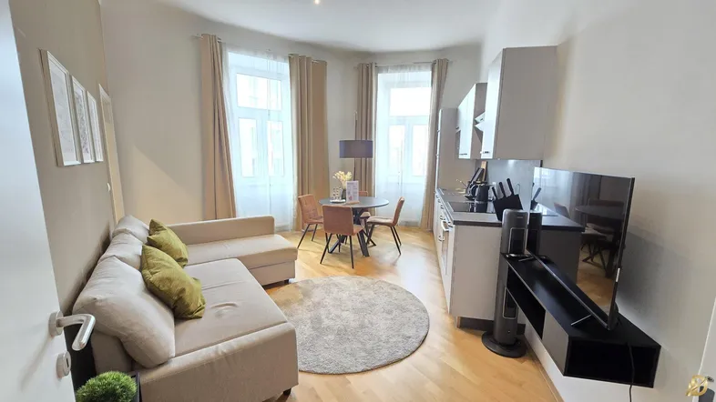 Helles und modernes Wohn-Esszimmer mit integrierter Küchenzeile, beigem Sofa und Holzboden.