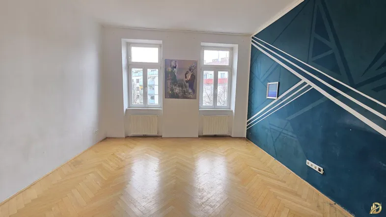 Helles Zimmer mit Fischgrätparkett und einer Wand mit modernem geometrischem Muster.