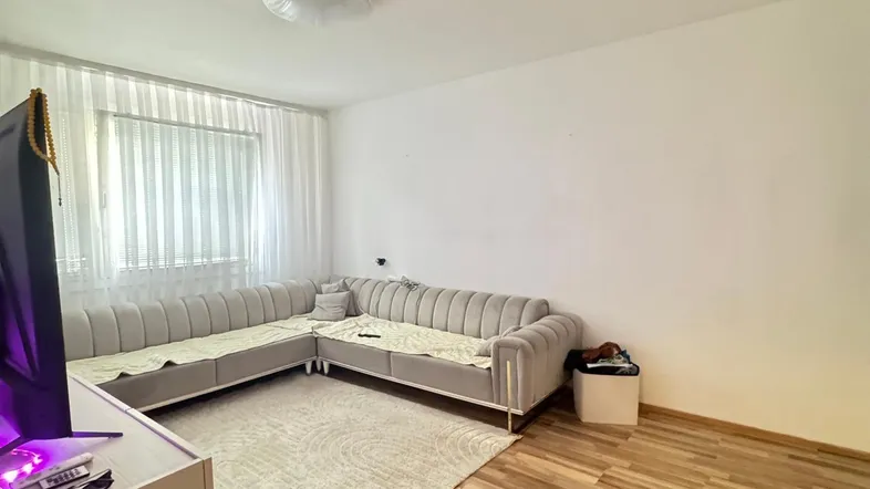 Helles Wohnzimmer mit modernem Ecksofa, Holzboden und großen Fenstern, die viel Tageslicht hereinlassen.