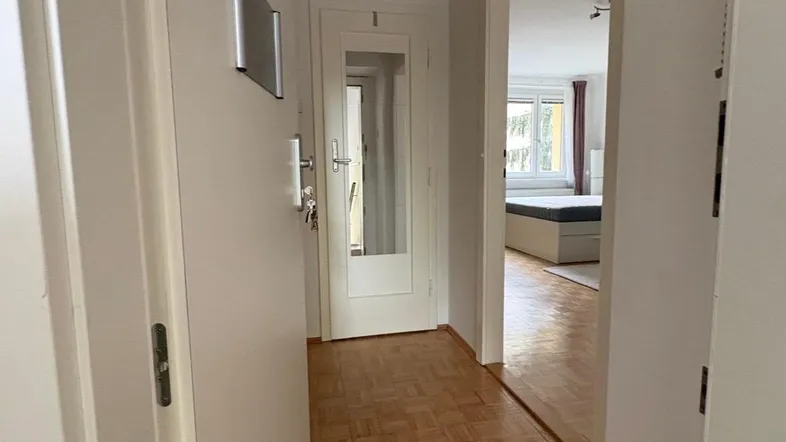 Heller Flur mit Parkettboden, der zu einem Schlafzimmer führt und eine freundliche Atmosphäre schafft.