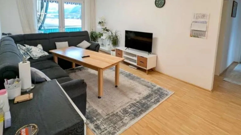 Helles Wohnzimmer mit bequemer Sofalandschaft, Holzboden und Blick auf die umliegende Natur.