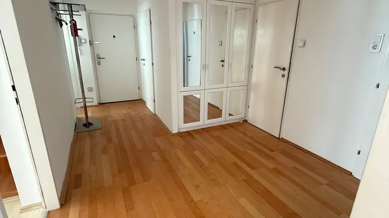 Heller Flur mit Holzparkettboden und einem praktischen Einbauschrank mit Spiegeltüren.