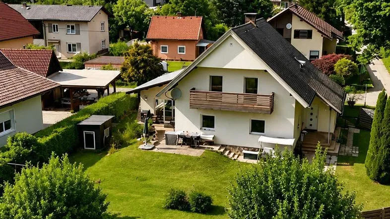 Luftaufnahme eines Einfamilienhauses mit großem Garten und Blick auf die umliegende Hügellandschaft.