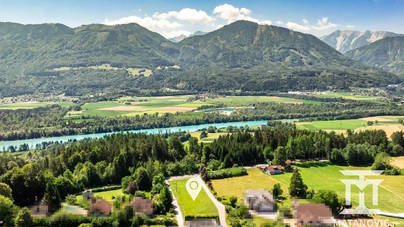Luftaufnahme eines Grundstücks in ländlicher Umgebung mit Bergen, Fluss und Wäldern im Hintergrund.