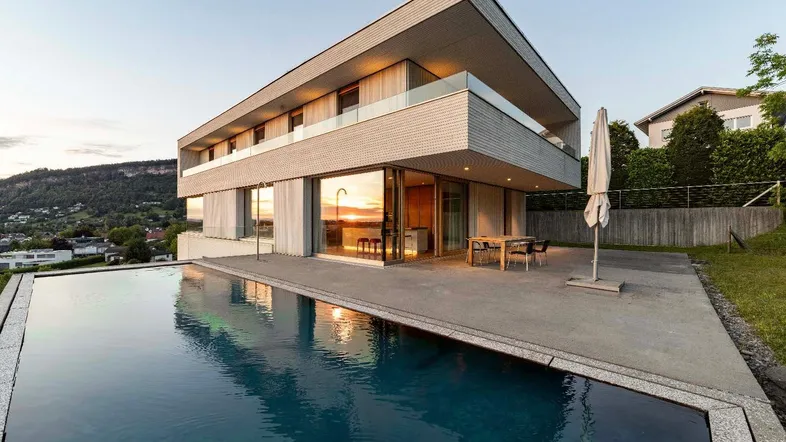 Moderne Villa mit Infinity-Pool und großer Terrasse, die einen weiten Blick auf die Landschaft bietet.
