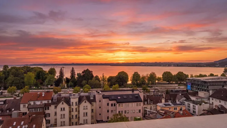 Atemberaubender Sonnenuntergang über dem Bodensee mit Blick auf die Stadt und die umliegende Landschaft.