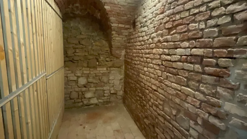Historischer Kellerraum mit freiliegenden Ziegelwänden, Gewölbedecke und Terrakottafliesen.