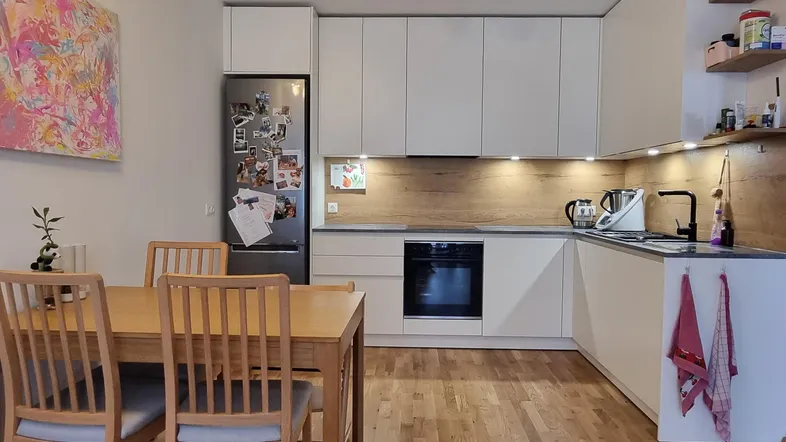 Moderne Küche mit weißen Schränken, Holzboden und integriertem Essbereich für die Familie.