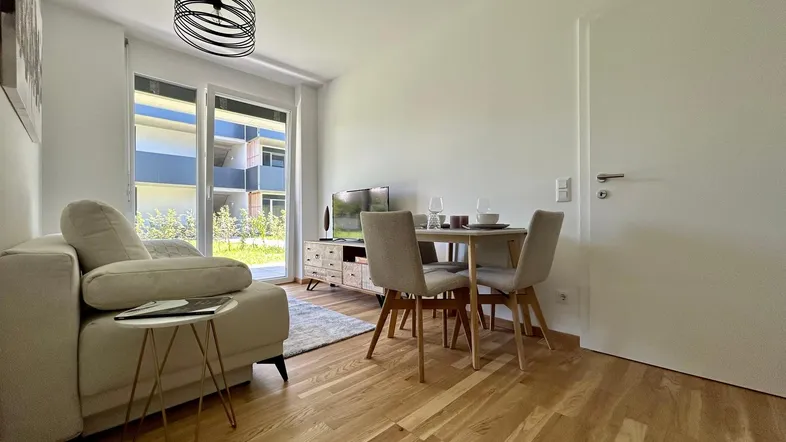 Helles Wohn- und Esszimmer mit Holzboden und Zugang zum Außenbereich.