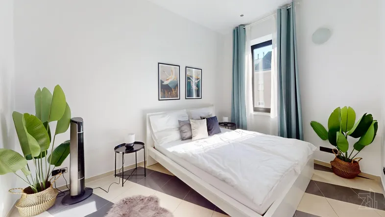 Helles Schlafzimmer mit modernem Bett, Pflanzen und stilvollen Bildern an der Wand.