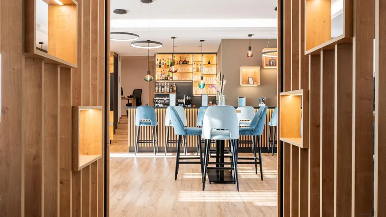 Moderne Bar mit blauen Samtstühlen und Holzvertäfelung, ideal für gesellige Abende.