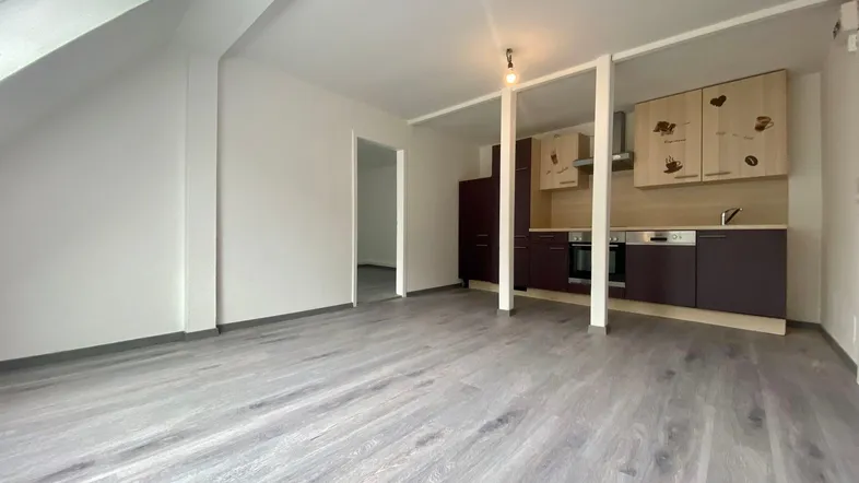 Helles Dachgeschosszimmer mit integrierter Küchenzeile und modernem Laminatboden in offener Gestaltung.