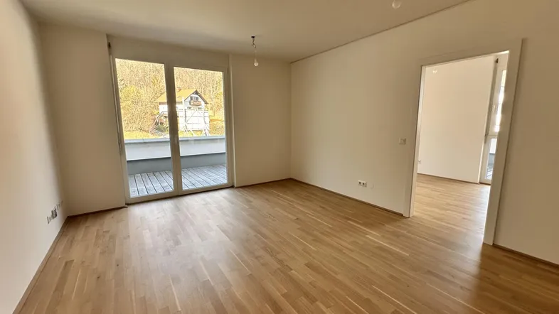 Helles Wohnzimmer mit Eichenparkett und Zugang zu einer großzügigen Dachterrasse.