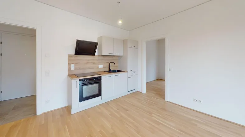 Moderne, helle Küchenzeile mit Holzoptik-Arbeitsplatte und integrierten Geräten in einem offenen Raum.