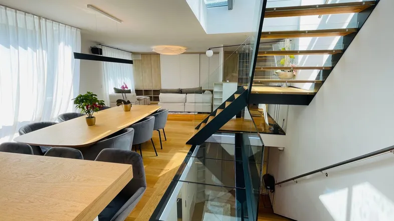 Offener Wohn-Essbereich mit moderner Küche, eleganter Treppe und viel Tageslicht.