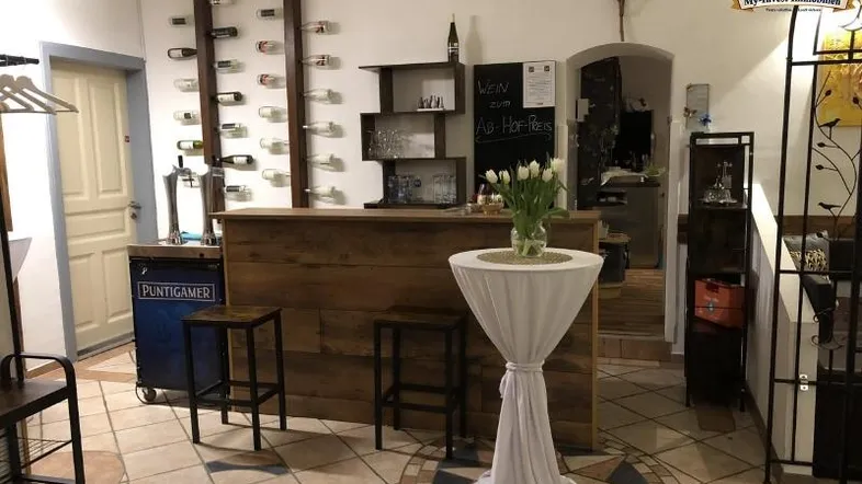 Gemütlicher Barbereich mit Holztresen, Weinflaschenregalen und dekorativen Elementen, ideal für gesellige Abende.