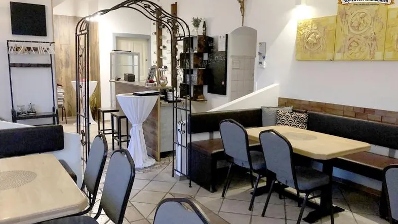 Gemütlicher Restaurantbereich mit Holztischen, gepolsterten Bänken und dekorativen Elementen, ideal für Gäste.