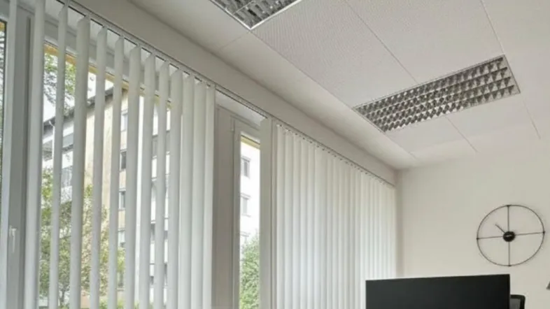 Helles und modernes Büro mit großen Fenstern, Holzfußboden und zeitgemäßer Einrichtung.