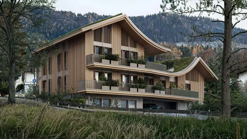 Modernes Gebäude mit Holzfassade, begrüntem Dach und Balkonen vor einer Bergkulisse.