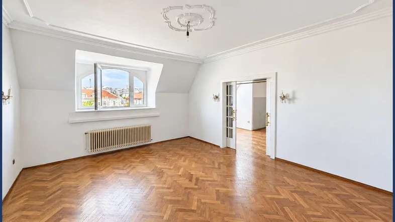 Helles Zimmer mit Fischgrätparkett, Stuckdecke und Fenster mit Blick auf die Stadt.