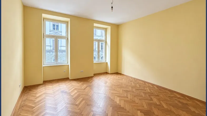 Helles, leeres Zimmer mit gelben Wänden und Fischgrätparkett, bereit zur individuellen Gestaltung.