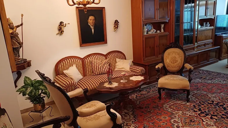 Traditionelles Wohnzimmer mit antiken Möbeln, einem großen Teppich und einem Kronleuchter.